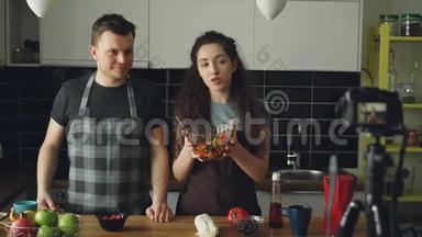 快乐有吸引力的一对夫妇在家里用数码<strong>相机录制</strong>关于健康烹饪的视频食物